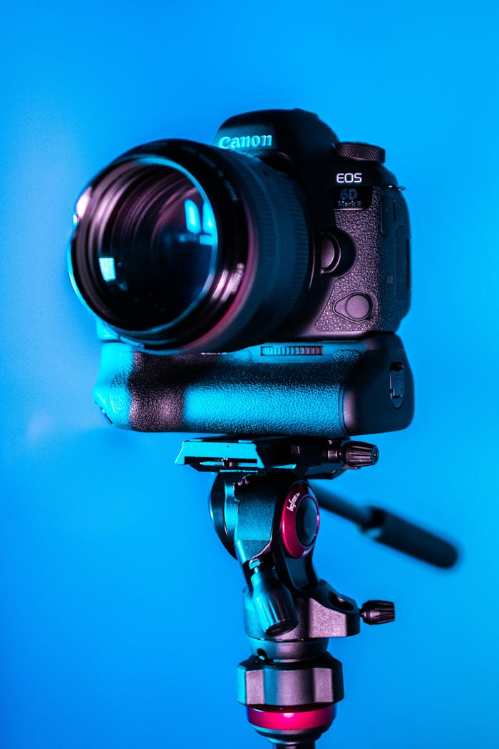 Services Close-up of a DSLR camera on a tripod with a blue background.